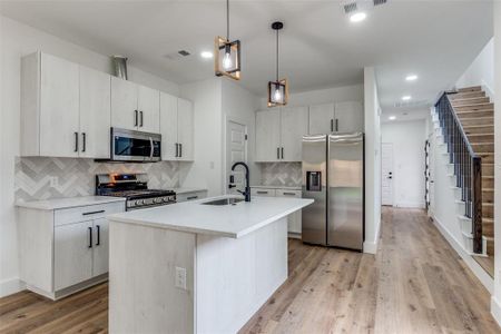 Kitchen with decorative backsplash, a sink, Samsung appliances with stainless steel finishes, light wood-style floors, and visible vents. Pantry in kitchen. Gas Range Kitchen with decorative backsplash, a sink, Samsung appliances with stainless steel finishes, light wood-style floors, and visible vents. Pantry in kitchen. Gas Range