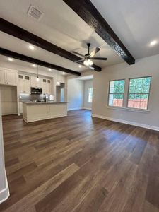 Unfurnished living room featuring dark hardwood / wood-style floors, beamed ceiling, sink, and ceiling fan