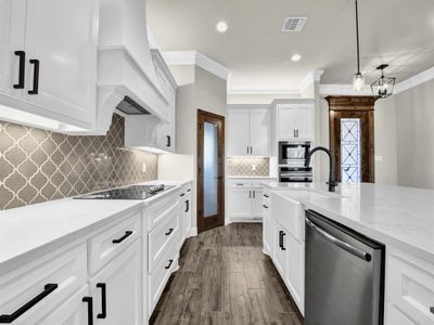 Kitchen featuring hanging light fixtures, stainless steel appliances, light stone counters, white cabinets, and custom exhaust hood