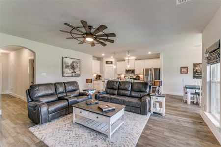 Living room with ceiling fan, light hardwood / wood-style flooring, and a wealth of natural light