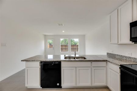 Kitchen featuring kitchen peninsula, sink, white cabinetry, and black appliances