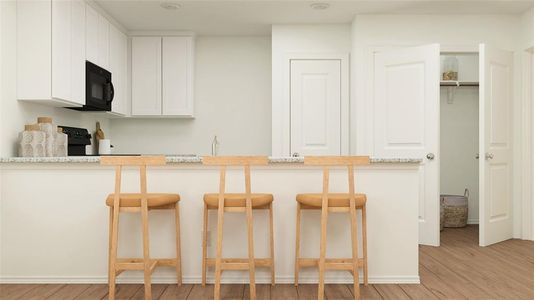 Kitchen featuring a breakfast bar area, light stone countertops, white cabinets, and light hardwood / wood-style floors