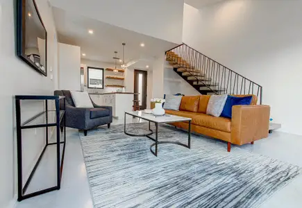 Living room featuring finished concrete floors, recessed lighting, and stairway