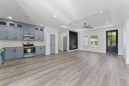 Kitchen featuring appliances with stainless steel finishes, a raised ceiling, light hardwood / wood-style floors, and ceiling fan