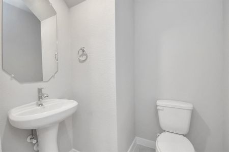 Immerse yourself in modern elegance within this delightful half bathroom. Featuring a sophisticated 5-panel door, upgraded pedestal sink, contemporary hardware, and stylish vanity lights, it exudes a sense of refinement. Sample photo of completed home with similar floor plan. Actual colors and selections may vary.