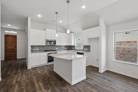 Kitchen featuring visible vents, lofted ceiling, dark wood-style floors, a kitchen island, and stainless steel appliances