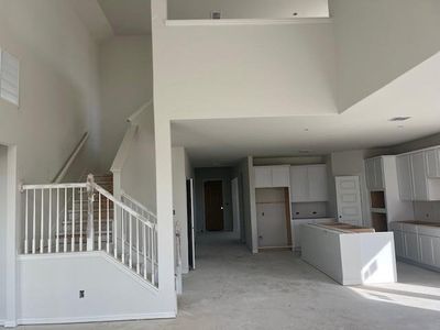 Kitchen with concrete flooring, white cabinetry, a kitchen island, and a high ceiling