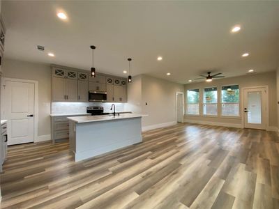 Kitchen with stainless steel appliances, hardwood / wood-style flooring, ceiling fan, and a kitchen island with sink