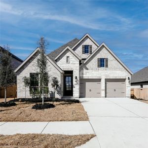 French country inspired facade with concrete driveway, stone siding, an attached garage, and fence