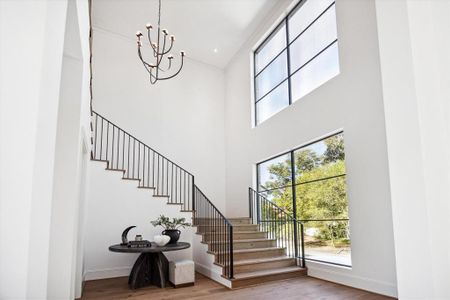 The double-height staircase creates a stunning entryway, accented by two sets of windows that fill the space with natural light and a striking chandelier overhead. It provides a grand sense of arrival while offering convenient access to the formal powder room. This elegant design sets the tone for the rest of the home.