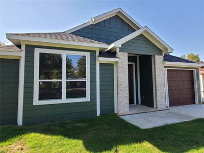 View of front facade featuring a garage and a front lawn