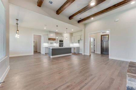 Unfurnished living room with beamed ceiling and light hardwood / wood-style floors