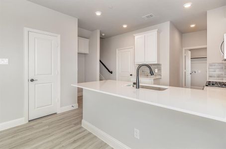 Kitchen with white cabinetry, decorative backsplash, light wood-type flooring, sink, and kitchen peninsula