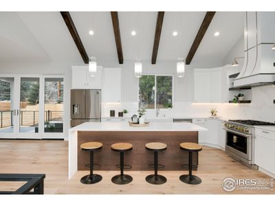 Gather friends and family in the heart of the home to enjoy the chef's kitchen with Monogram gas range, designer custom hood, custom cabinets and single slab island.