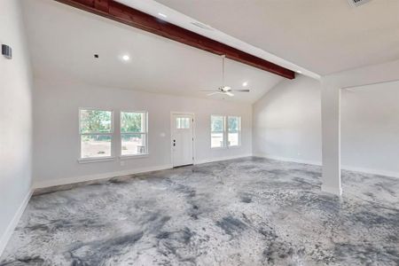 Unfurnished living room with vaulted ceiling with beams, ceiling fan, and a healthy amount of sunlight