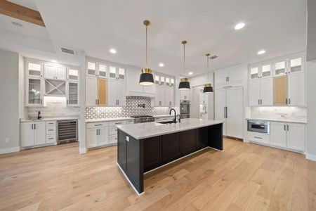 Beautiful kitchen with built in fridge, built in microwave, touch faucet, water filter, 2 stoves, 6 grill cooktop with pot filler, and a bar with a wine fridge.