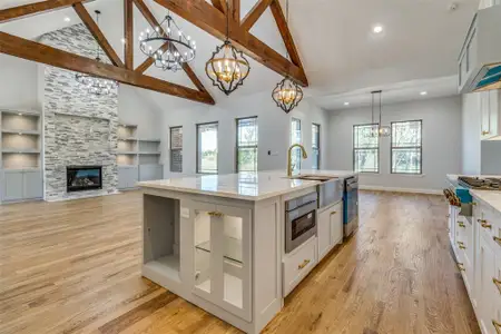 Kitchen featuring light hardwood / wood-style floors, decorative light fixtures, built in shelves, and a center island with sink