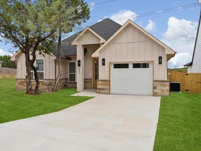 View of front of property with central AC unit, a garage, and a front lawn