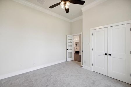 Unfurnished bedroom featuring a closet, ceiling fan, crown molding, light colored carpet, and a towering ceiling