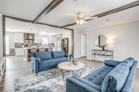 Living room featuring ceiling fan, beamed ceiling, light hardwood / wood-style floors, and ornamental molding