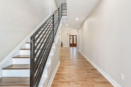 Staircase featuring an inviting chandelier and hardwood / wood-style flooring