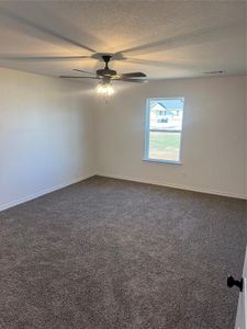 Empty room with ceiling fan, dark colored carpet, and a textured ceiling