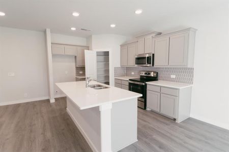 Kitchen with stainless steel appliances, light hardwood / wood-style floors, a center island with sink, and sink