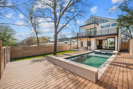 Back of house featuring a pool with connected hot tub, stucco siding, a fenced backyard, a balcony, and a patio