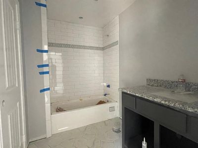 Bathroom featuring vanity, tiled shower / bath, and tile patterned floors