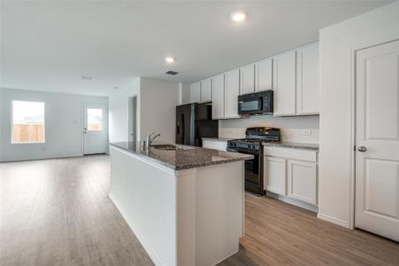 Kitchen with white cabinets, a kitchen island with sink, and black appliances