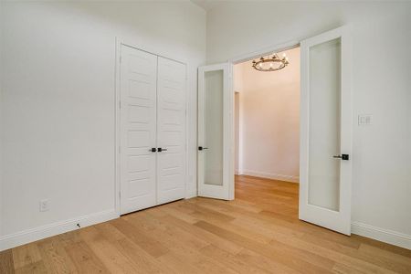 Unfurnished bedroom with light hardwood / wood-style flooring, a closet, and a chandelier