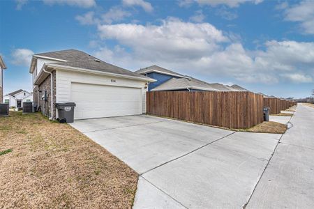 View of home's exterior featuring brick siding, central AC unit, concrete driveway, garage door and fence