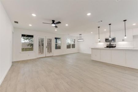 Unfurnished living room with ceiling fan, plenty of natural light, sink, and light hardwood / wood-style floors