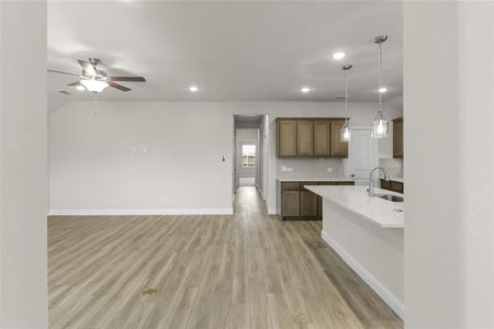 Kitchen with ceiling fan, tasteful backsplash, light wood-type flooring, pendant lighting, and sink