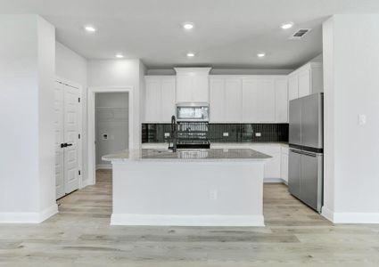 Stunning kitchen with a large granite island, tile backsplash, and wood flooring.