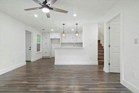 Unfurnished living room featuring ceiling fan and dark hardwood / wood-style flooring