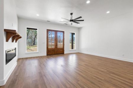 Unfurnished living room with hardwood / wood-style flooring, ceiling fan, heating unit, and french doors