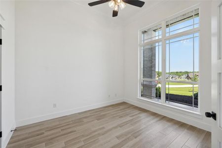 Unfurnished room with a wealth of natural light, light hardwood / wood-style flooring, ceiling fan, and crown molding