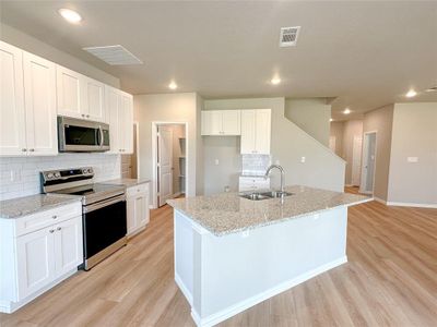 Kitchen with sink, light wood-type flooring, a kitchen island with sink, and appliances with stainless steel finishes