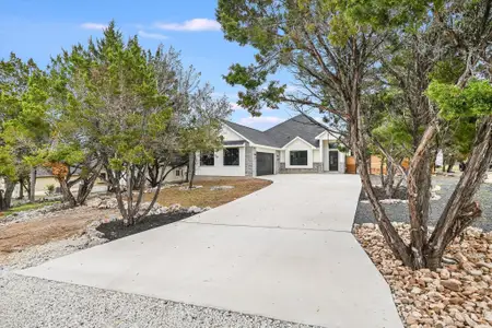 View of front of home with a garage, driveway, and stone siding