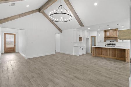 Unfurnished living room with high vaulted ceiling, a chandelier, light hardwood / wood-style flooring, and beam ceiling