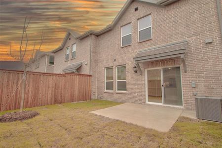 Back house at dusk featuring central air condition unit, a patio area, and a yard