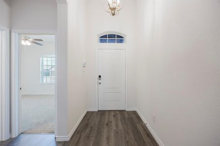 Doorway with ceiling fan with notable chandelier and dark hardwood / wood-style floors