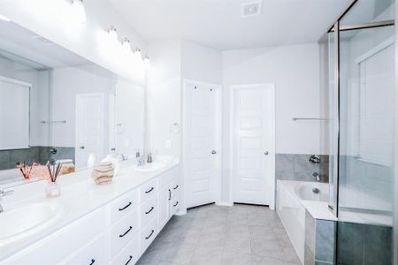 Bathroom featuring tiled tub, tile patterned flooring, and vanity