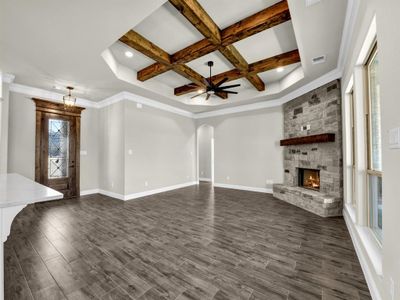 Unfurnished living room featuring beamed ceiling, a fireplace, plenty of natural light, and coffered ceiling