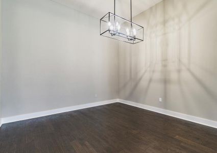 Formal dining room with wood flooring and a black iron chandelier.