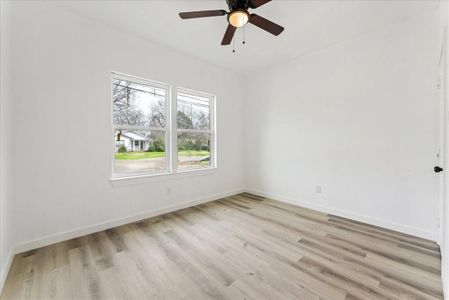 Spare room with light wood-style flooring, baseboards, and a ceiling fan