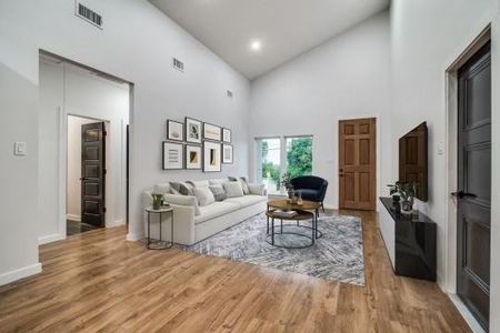 Living room with wood-type flooring and high vaulted ceiling