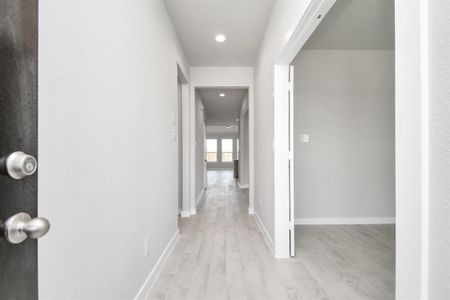 The grand entrance beckons with high ceilings, adorned with elegant wood-look tile flooring and oversized baseboards, and recessed lighting. Follow path of natural light from expansive windows ahead. Sample photo of completed home with similar floor plan. Actual colors and selections may vary.