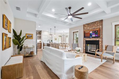 Upon entering, the great room wows with its coffered ceiling and cozy wood burning fireplace.